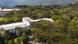 A modern building with a flat roof, surrounded by dense greenery and hills in the background.