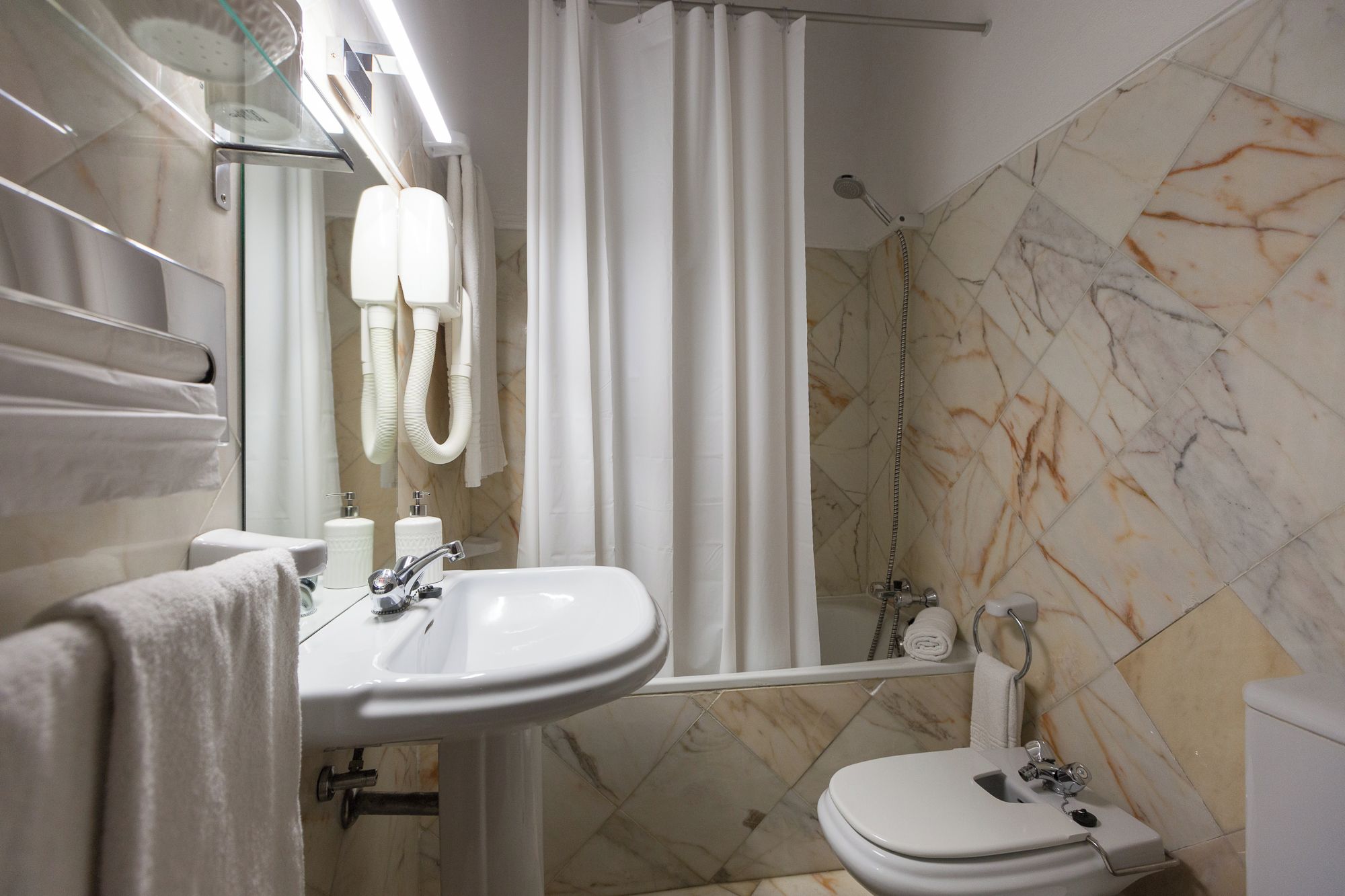 A bathroom with a sink, toilet, shower, and a mirror.