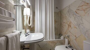 A bathroom with a sink, toilet, shower, and a mirror.