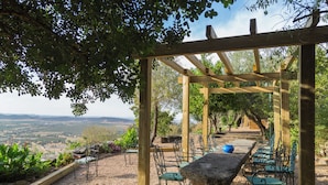 Una pérgola con una mesa y sillas, con vistas a un paisaje pintoresco.