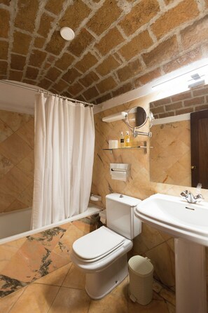 A bathroom with a shower curtain, toilet, sink, and a mirror. - Estalagem de Monsaraz (Reguengos de Monsaraz)