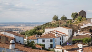 Un pueblo histórico con edificios blancos, una iglesia destacada y vistas al campo.