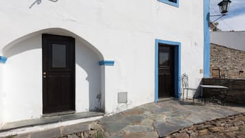 A building with a white exterior, two dark doors, stone steps, and a stone wall.