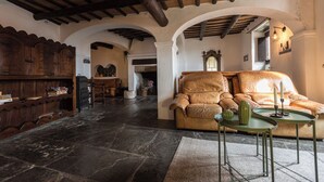 Una sala de estar acogedora con un sofá de cuero, un aparador de madera y suelo de piedra.
