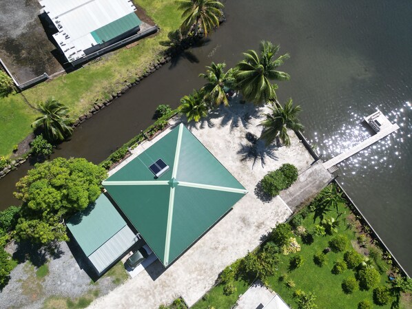 An aerial view of a building with a green roof, surrounded by palm trees and a body of water. - AUTE (Raiatea)