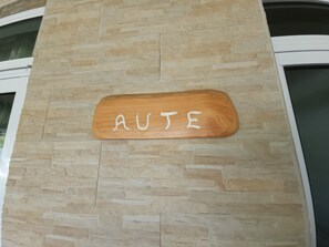 A wooden sign with the word "AUTO" mounted on a stone wall.