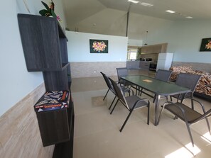 Un espace repas moderne avec une table rectangulaire, six chaises et un canapé agrémenté de coussins à motifs.