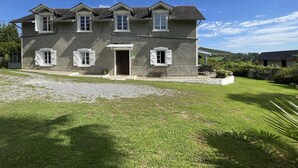 A two-story house with a stone facade, multiple windows with shutters, and a well-maintained lawn in front. - GITE DU BOSC - LYS - Gîte (LYS)