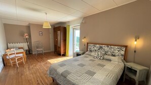 A bedroom with a large bed, a wooden desk, a chair, a wardrobe, and a window with curtains. - GITE DU BOSC - LYS - Gîte (LYS)