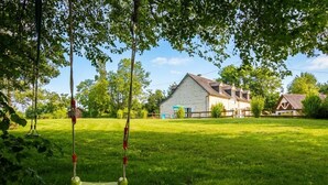 Een gazon met een schommel en een huis op de achtergrond.