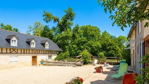 Een historisch vakwerkhuis met een grindpad, terras en houten omheining.