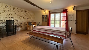 Een kamer met een houten bankje, een tafel, een muur met een stenen patroon, een raam met rode gordijnen en een deur.