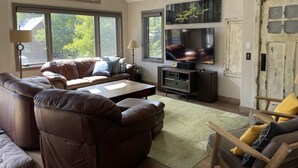 A living room with a large window, a sofa, a coffee table, and a television. - Crested Butte Home | 4 Bedroom | Hot Tub | Walk to Elk | Gas Grill |Pet-Friendly (Crested Butte)