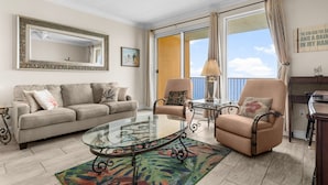 Un salon avec un canapé beige, une table basse en verre, un fauteuil beige et un grand miroir.