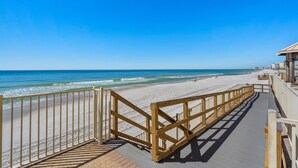 Un paseo marítimo de madera que conduce a una playa con un cielo azul despejado.