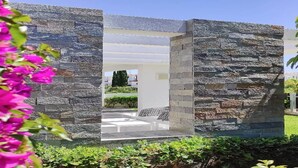 A stone structure with a clear view of an outdoor seating area and greenery. - Atlantis Gardens Resort (Mazotos)