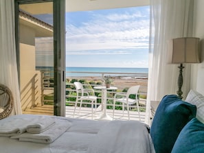 Une chambre d’hôtel avec un balcon donnant sur une plage.