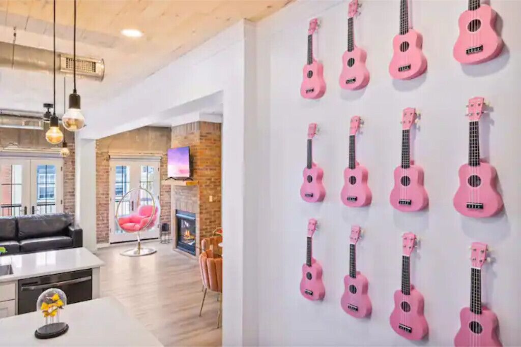 A modern living room with a fireplace, a hanging chair, and a wall-mounted guitar display.