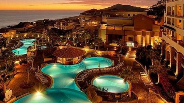 A resort with multiple swimming pools, a central gazebo, and surrounding buildings.