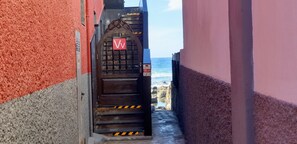 A narrow alleyway leading to a gated entrance with a view of the ocean. - Accommodations on the northeast coast of Gran Canaria, with unbeatable ocean views. (Moya)