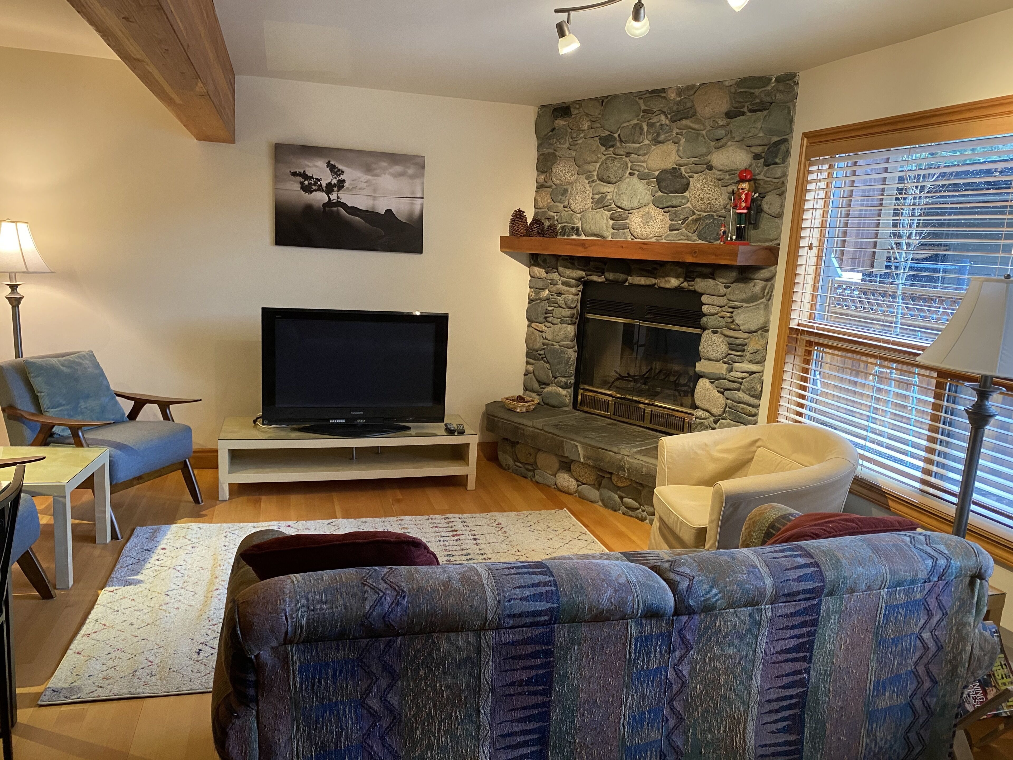 A living room with a stone fireplace, a flat-screen TV, and a sofa.