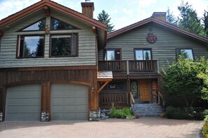 A two-story log cabin with a garage, a balcony, and a stone foundation.