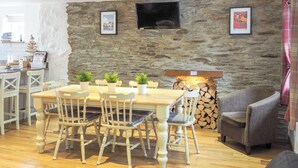 A dining area with a stone wall, a television, and a fireplace. - 3 bedroom accommodation in Rhoshill, near Cardigan (Rhoshill, near Cardigan)