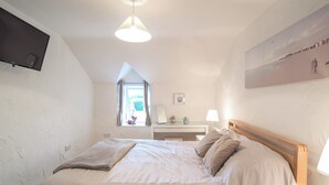 A bedroom with a large bed, a desk, a chair, a TV mounted on the wall, and a window with curtains. - 3 bedroom accommodation in Rhoshill, near Cardigan (Rhoshill, near Cardigan)