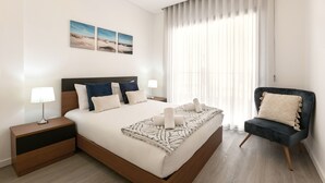A modern bedroom with a large bed, two bedside tables, a chair, and a view of the outdoors through sheer curtains.