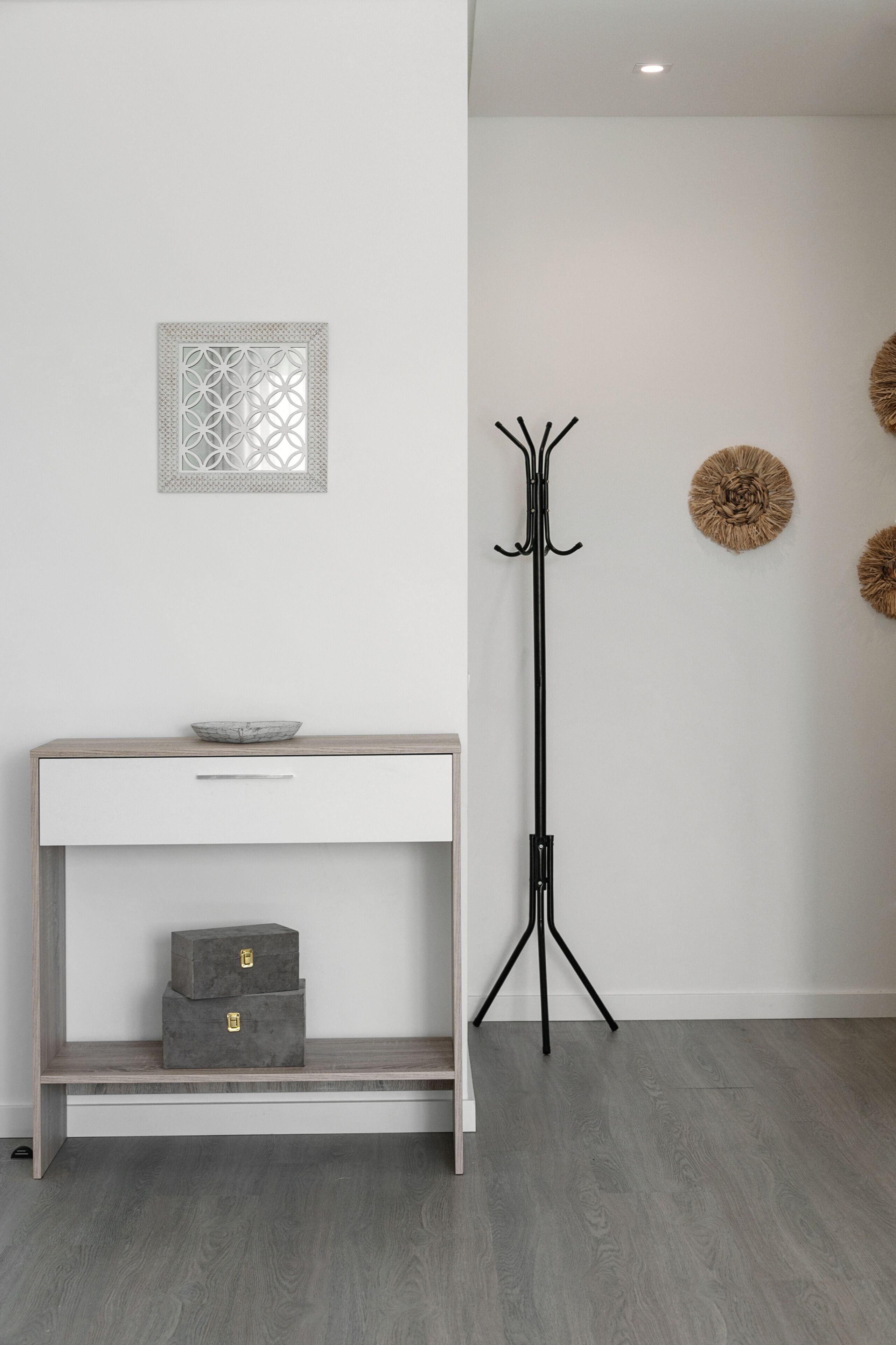 Une pièce au décor minimaliste, avec une console blanche, un lampadaire et des œuvres d’art décoratives accrochées au mur.