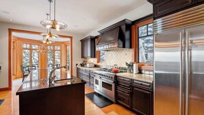 Una cocina moderna con una isla central, electrodomésticos de acero inoxidable y armarios oscuros.