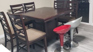 Un espace repas avec une table rectangulaire entourée de six chaises, dont une est une chaise rouge au design moderne.