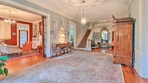 Un salon spacieux agrémenté d’un grand tapis, de meubles en bois et d’un escalier menant à un autre niveau.