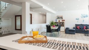 A modern kitchen with a dining area, a living room with a sofa and a coffee table, and a staircase. - Aromas de Alcala Alcalá La Real by Ruralidays (Jaén)