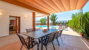 An outdoor dining area with a pool view, a covered patio, and a kitchen visible through an open door. - Aromas de Alcala Alcalá La Real by Ruralidays (Jaén)