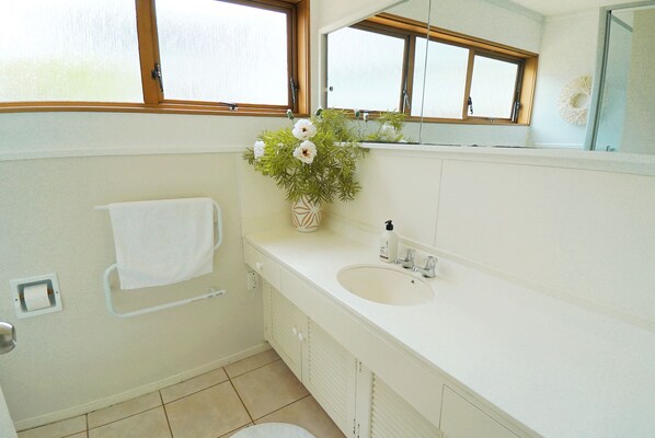 A bathroom with a white sink, a towel rack, a window, and a mirror.
