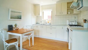 Une cuisine avec des meubles blancs, une table à manger en bois et des chaises.