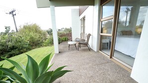 Une terrasse couverte avec une table et des chaises, une plante en pot et une vue sur la verdure environnante.