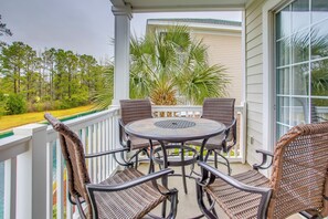 A covered outdoor patio with wicker furniture and a view of a forest. - Golf Resort Condo w/ Pool in North Myrtle Beach! (North Myrtle Beach)