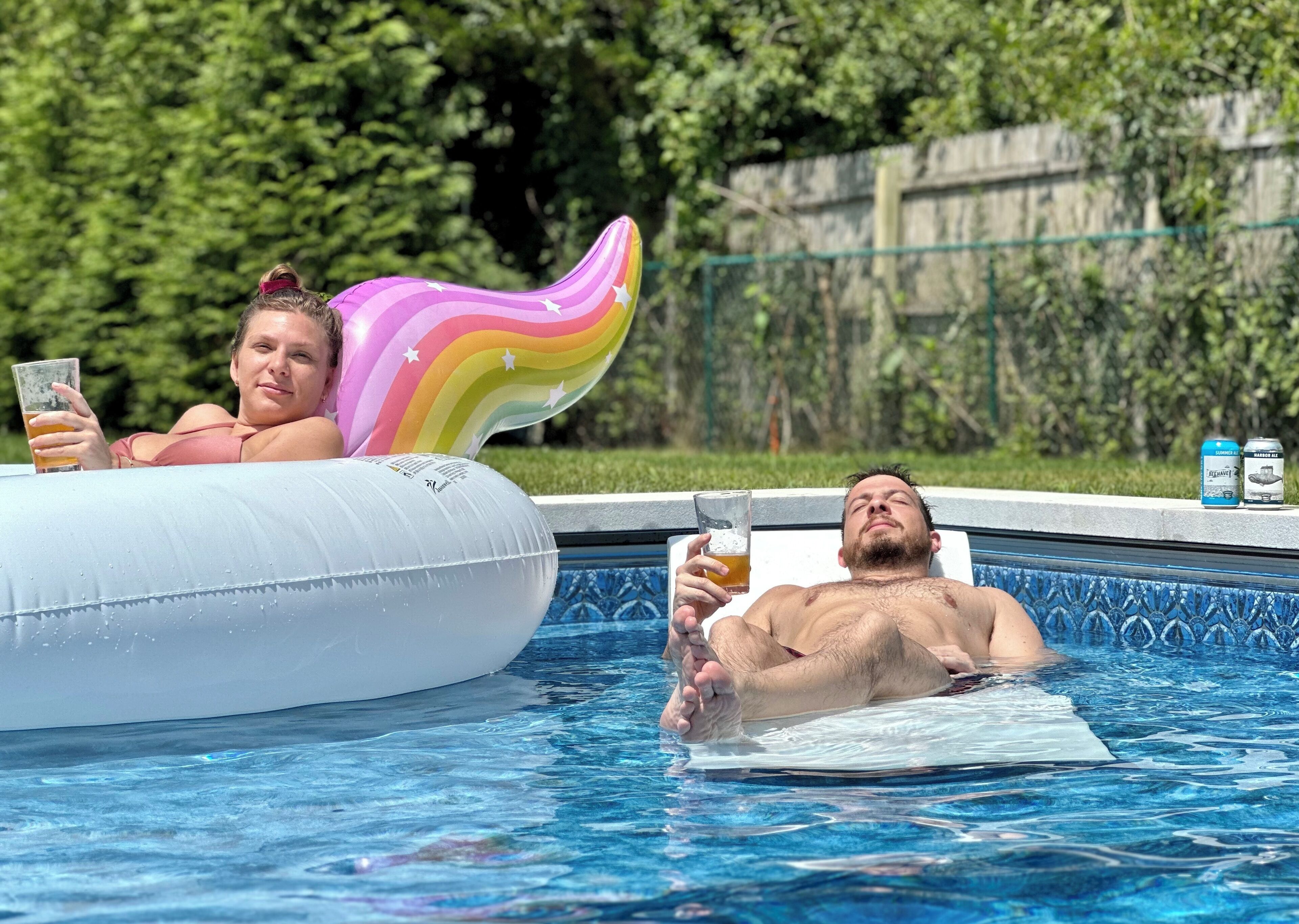 Piscina com boias infláveis e duas pessoas relaxando.