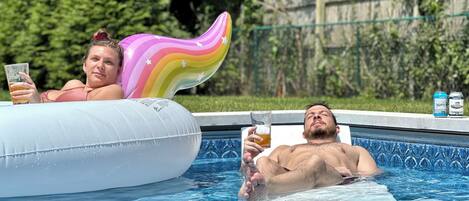 A swimming pool with inflatable floats and two people relaxing.