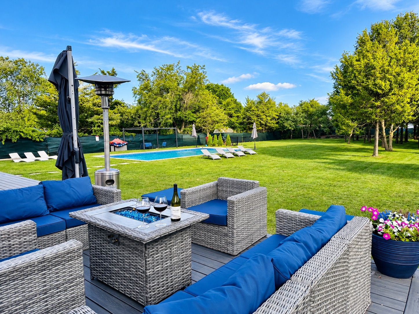 A patio area with wicker furniture, a pool, and a well-maintained lawn.