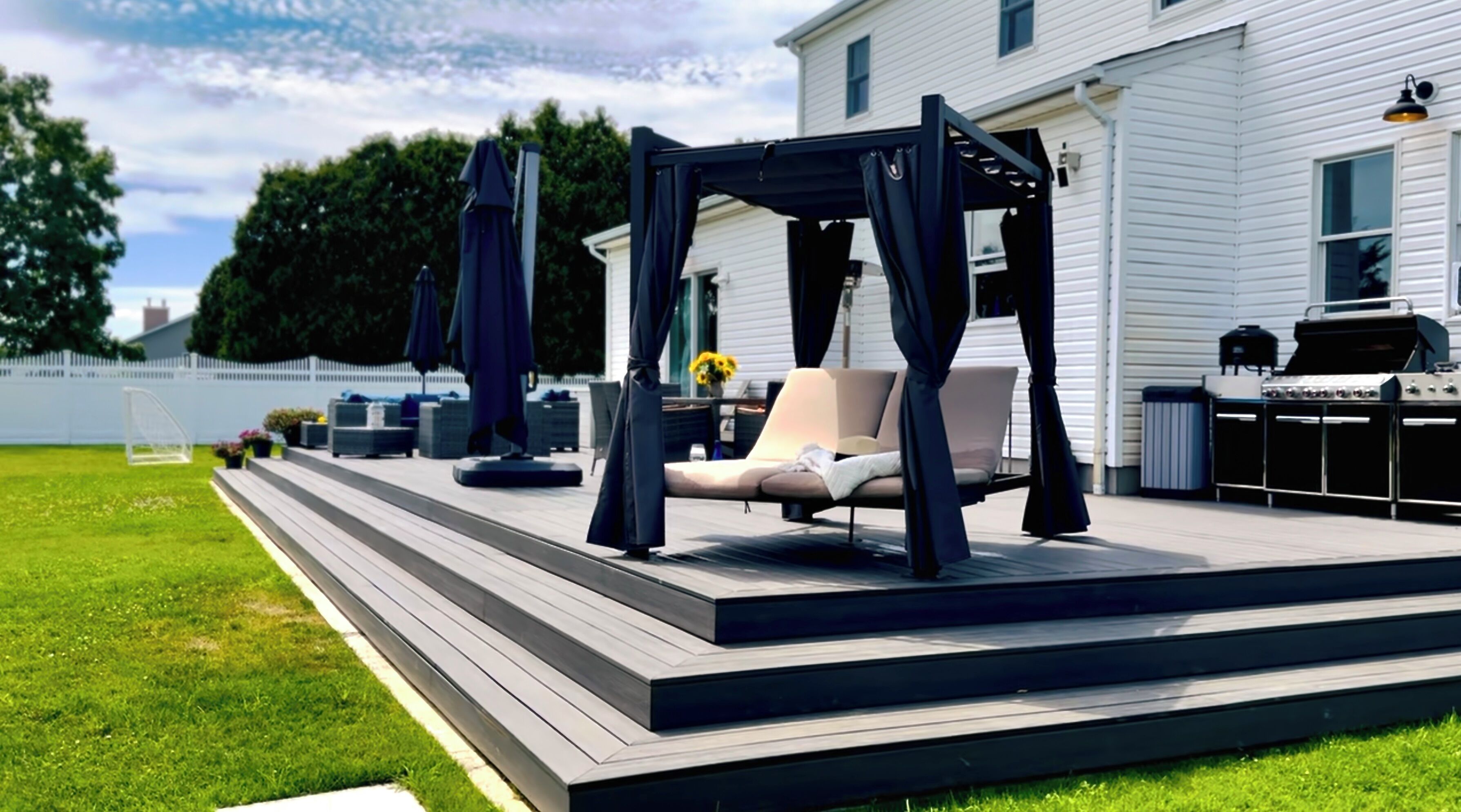 Una terraza con toldo, mobiliario exterior y una parrilla.