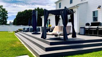 Una terraza con toldo, mobiliario exterior y una parrilla.