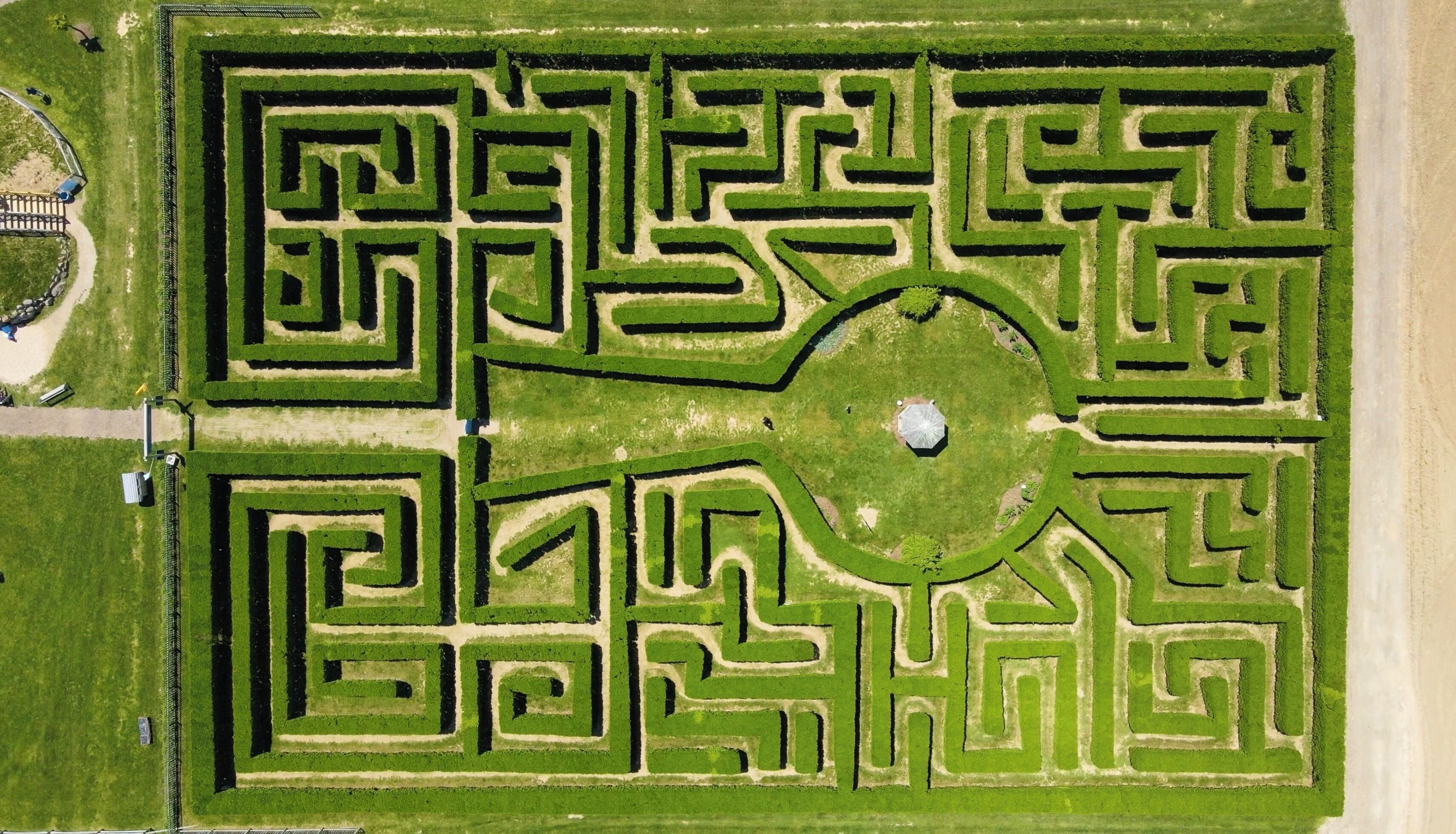 Vista aérea de un jardín laberinto con una zona circular central y senderos.