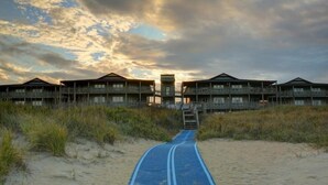 A pathway leading to a beachfront building with multiple balconies and a central tower. - Outer Banks Beach Club II - 1BR/1BA - Great Pools! (Kill Devil Hills)