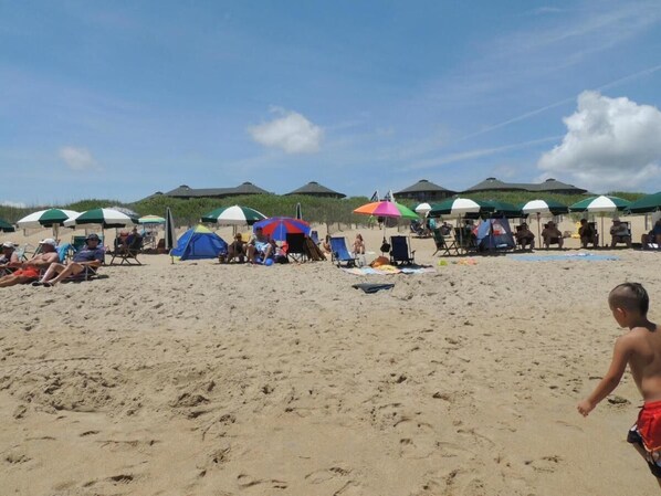 Una playa con tiendas de campaña y gente relajándose.