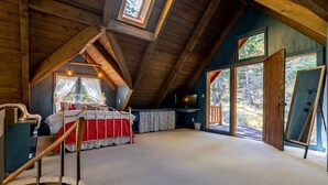 Un dormitorio en el ático con una cama litera, ventanas amplias y una escalera de madera.
