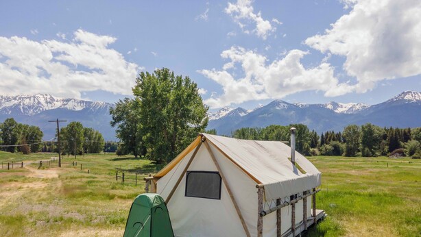 A small, single-room tent with a chimney, set in a grassy field with a mountain backdrop. - Glamping Tent on the Evans Farm near Joseph, Oregon. (joseph)