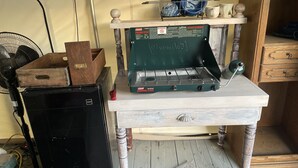A compact kitchen with a propane stove, a fan, and wooden furniture. - Glamping Tent on the Evans Farm near Joseph, Oregon. (joseph)
